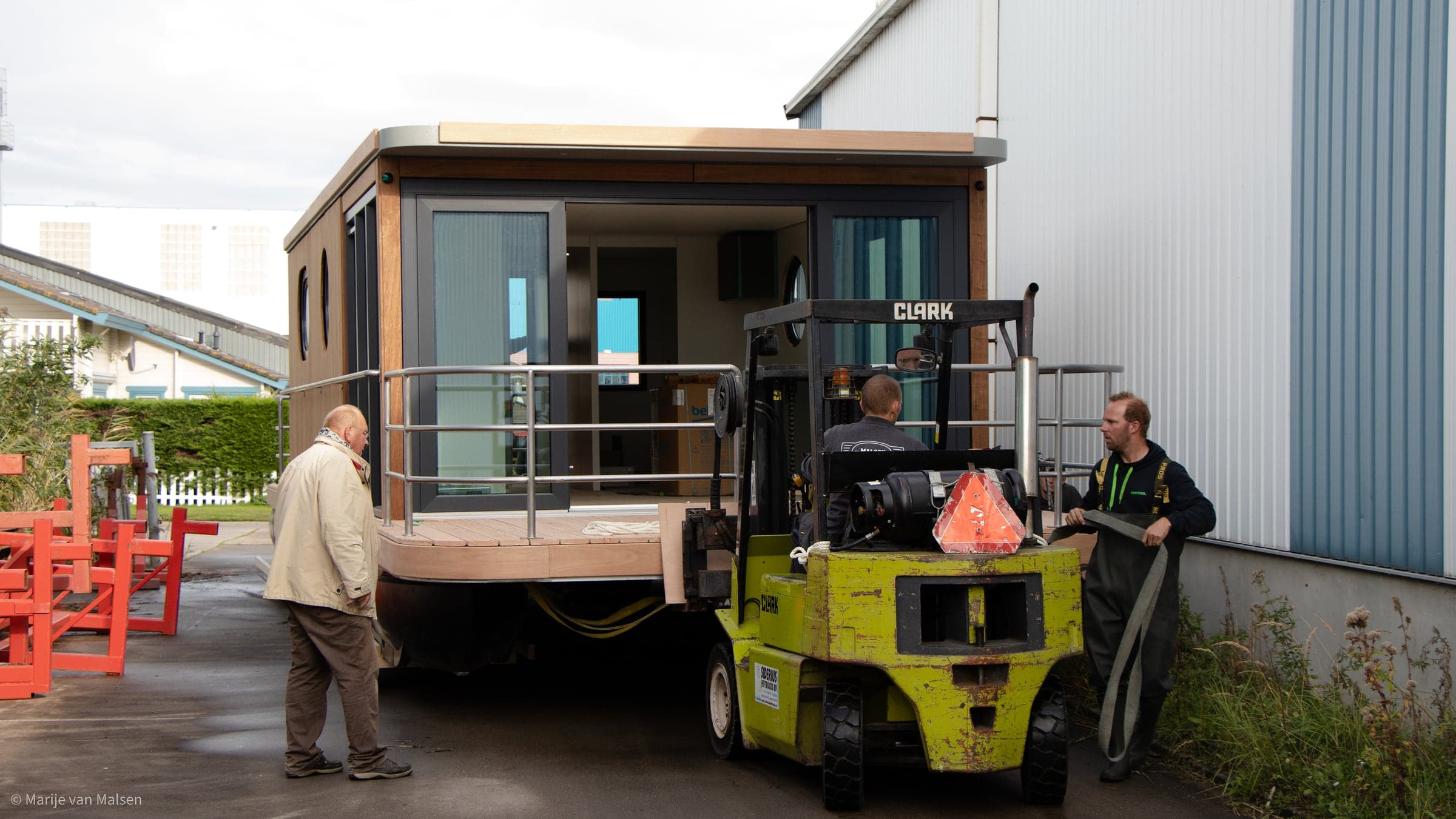 Het team verplaatst een woonboot met een heftruck
